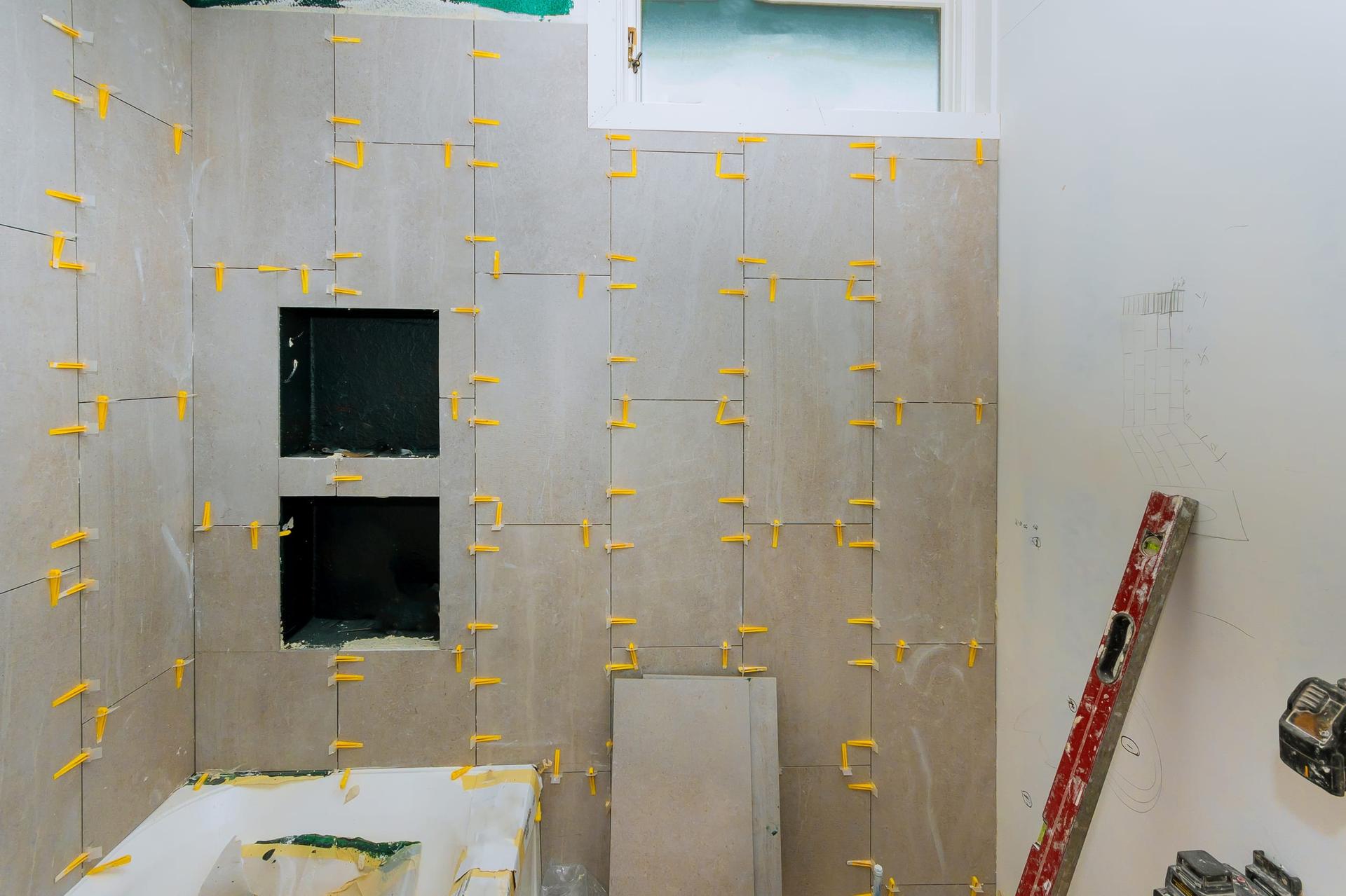 A bathroom mid-renovation with bare walls and partly laid floor and wall tiles.