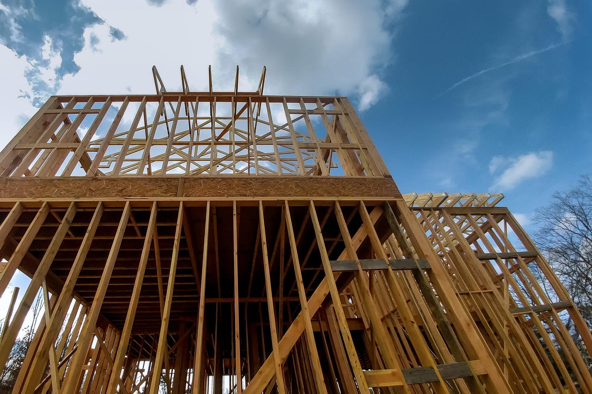 Construction work in progress on an unfinished house with wooden framing
