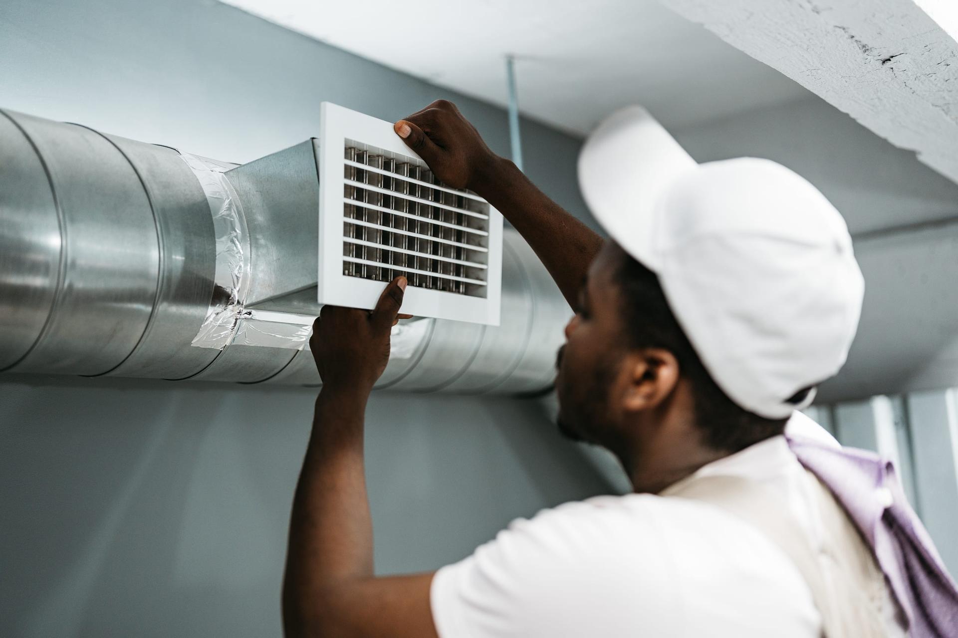 Technician removing a vent grille from exposed ductwork