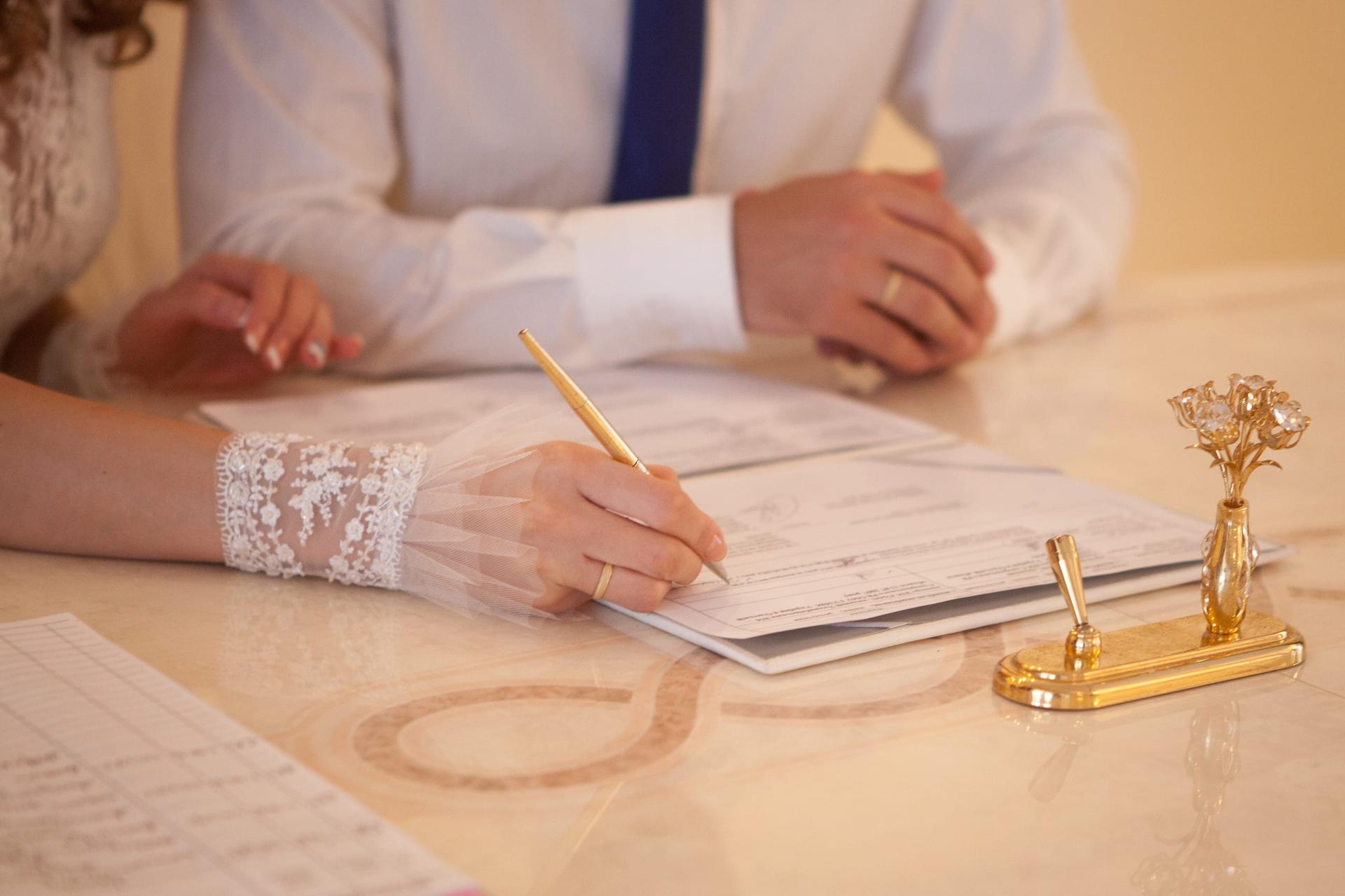 A bride and groom signing marriage papers at a registry table
