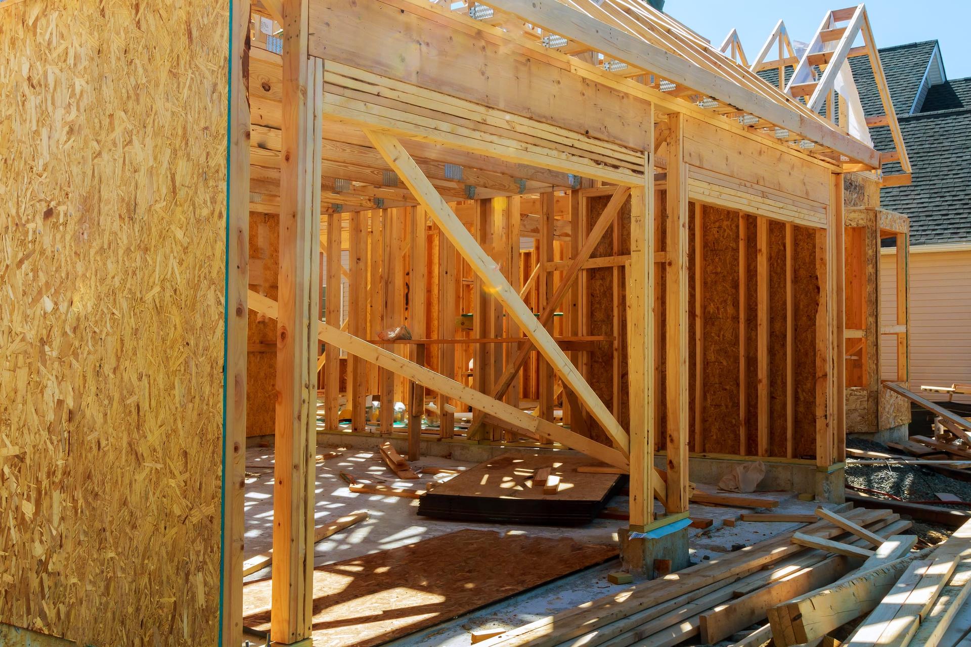 A new wood-framed house under construction with its stud walls and roof framing still exposed.