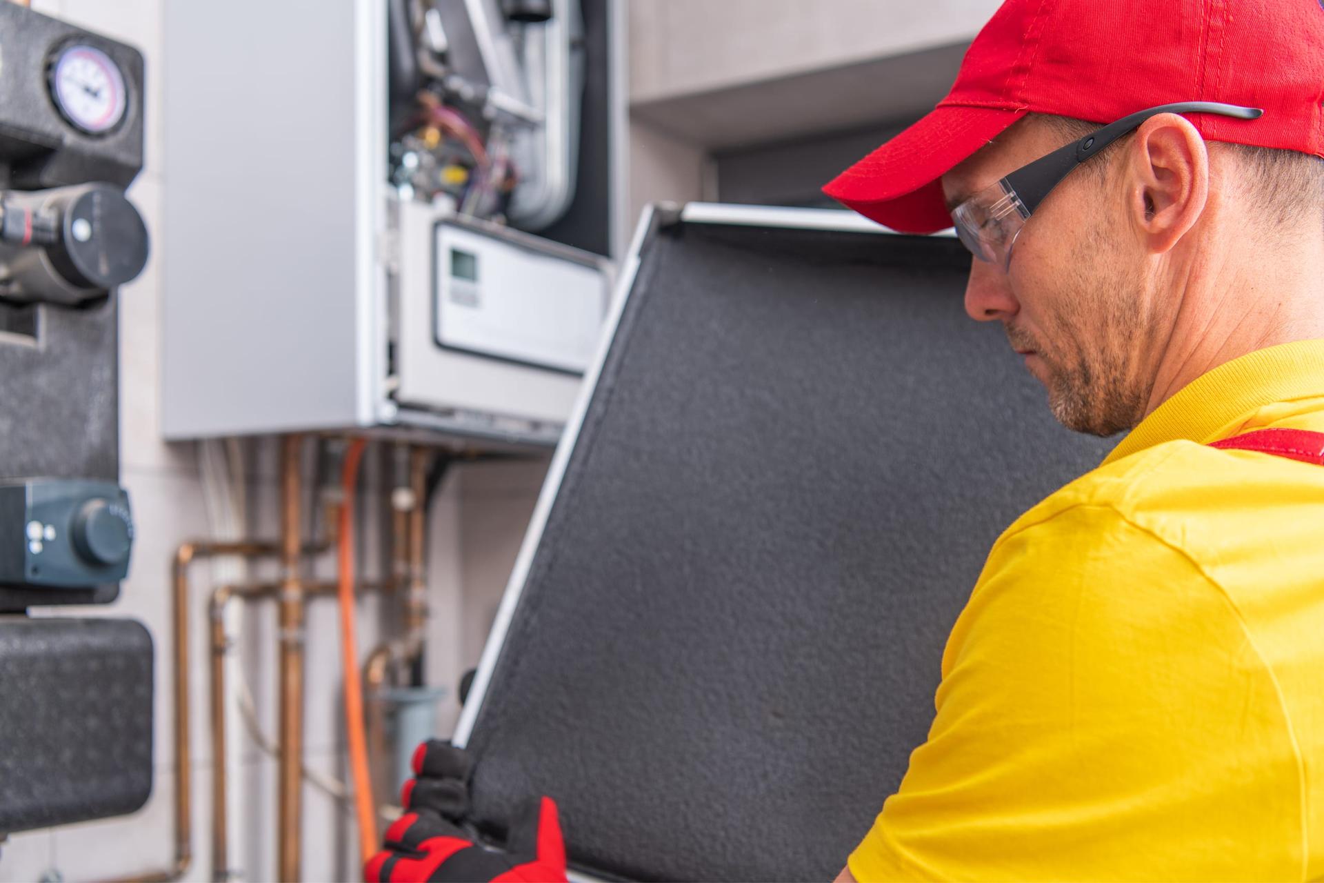 A worker fits a new component onto a residential heating and cooling unit.