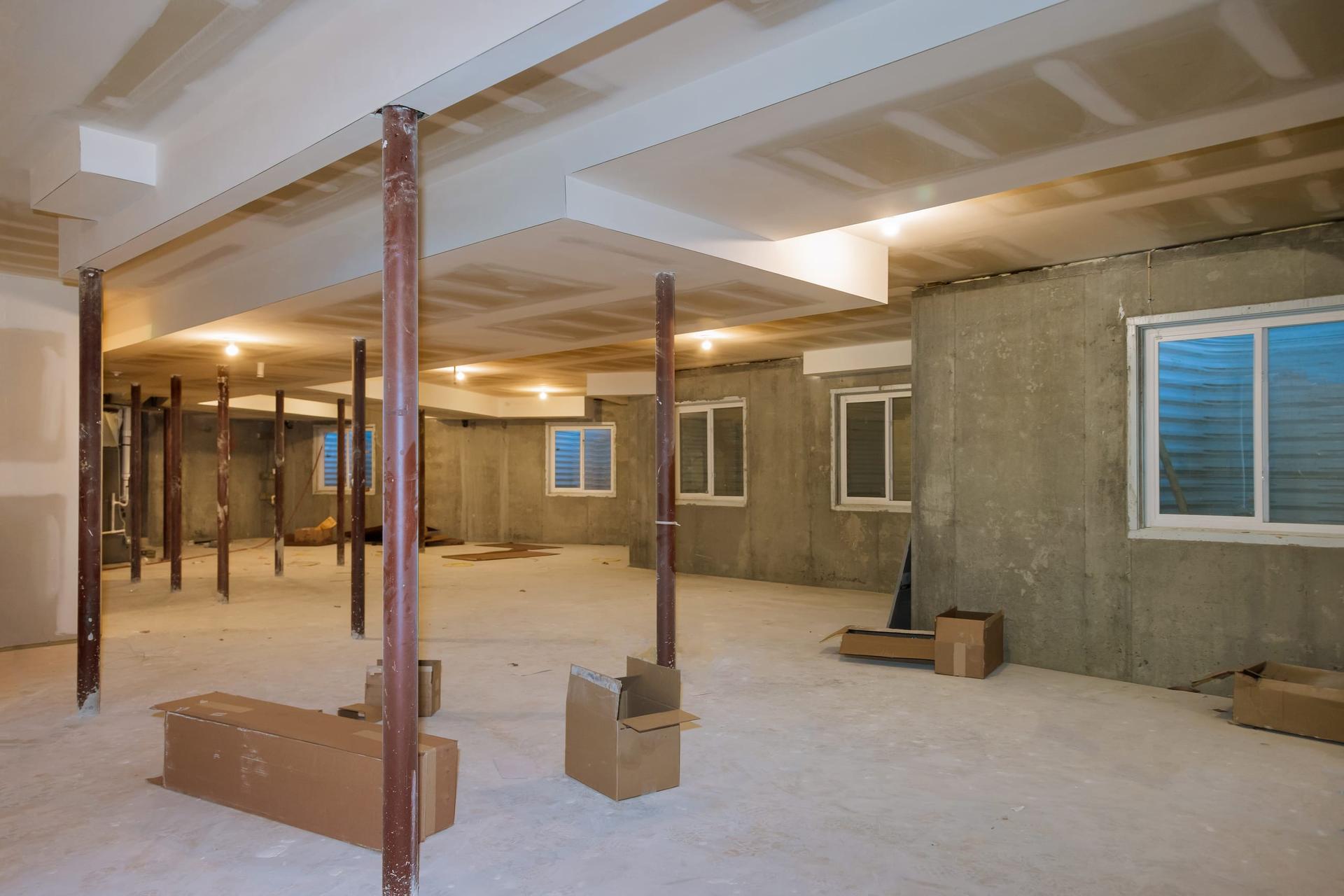 Unfinished basement of a house with bare concrete walls and support posts