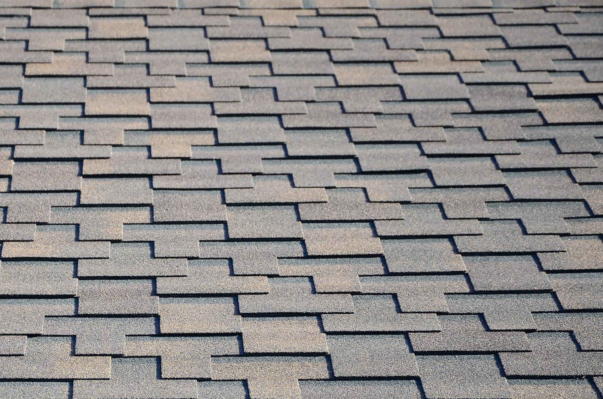 A close-up of grey and brown asphalt roof shingles