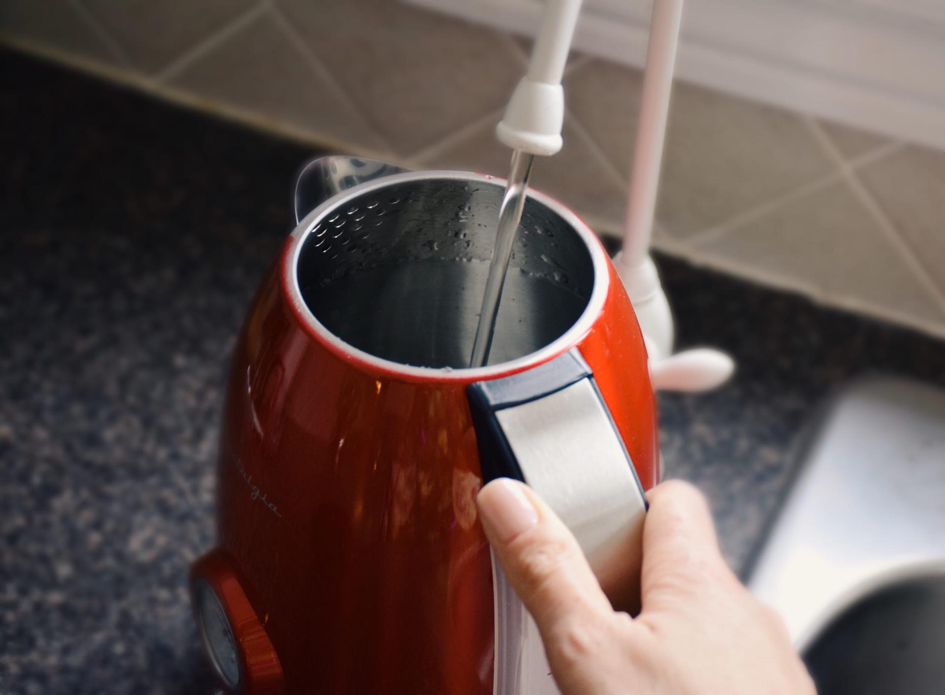 A kettle being filled from a kitchen tap