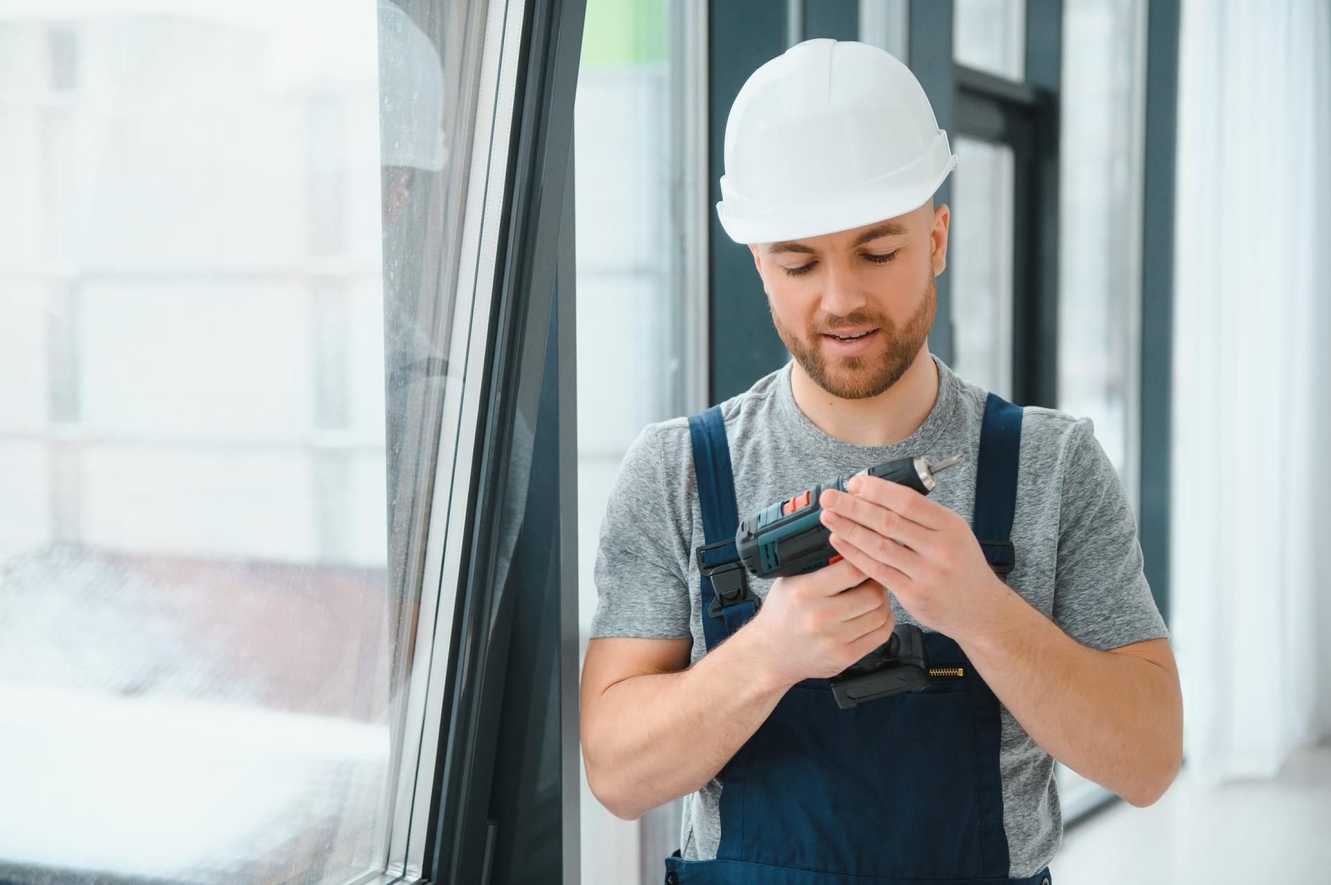 Window installer holding a drill beside new windows